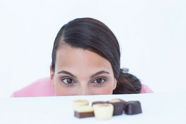 Photo of a beautiful brunette taking a peek at chocolate